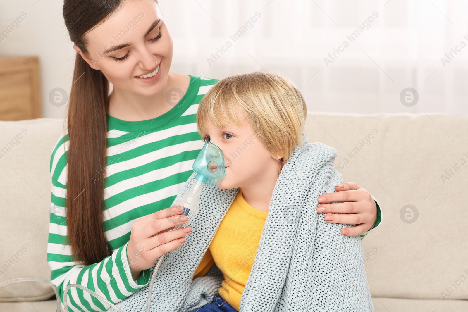 Photo of Mother helping her sick son with nebulizer inhalation at home