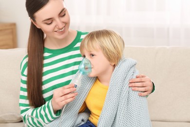 Photo of Mother helping her sick son with nebulizer inhalation at home