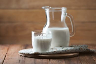 Photo of Tasty fresh milk in jug and glass on wooden table