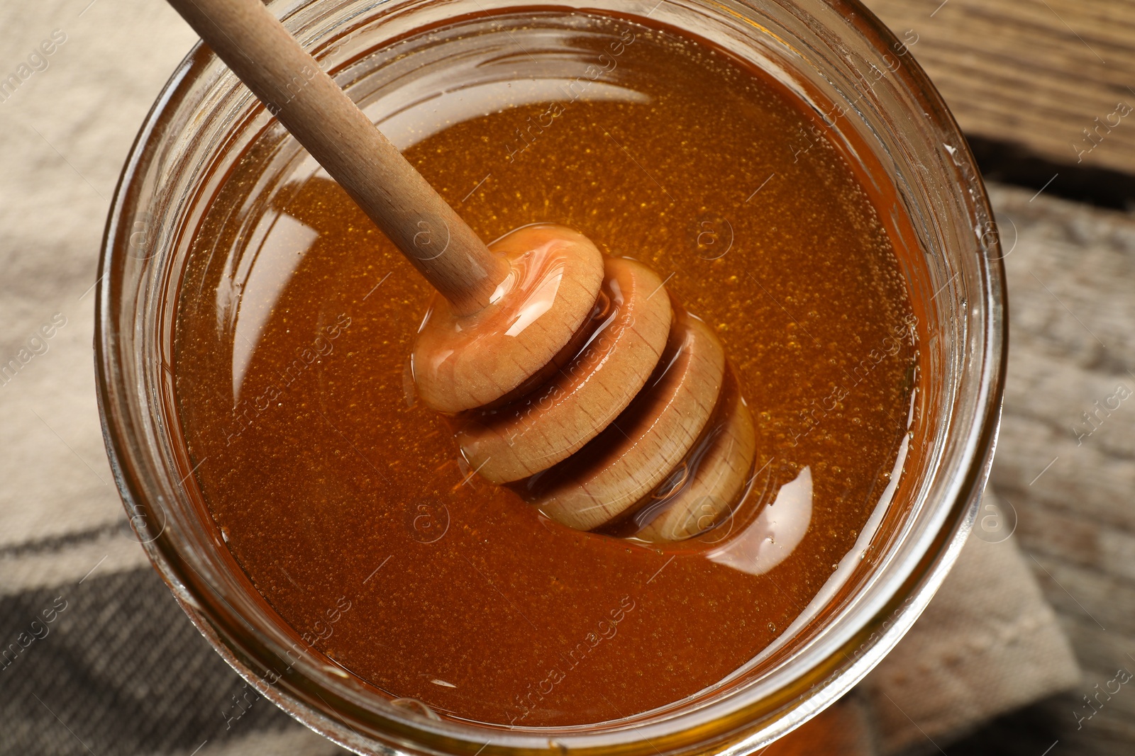 Photo of Dipper with honey in jar on table, top view