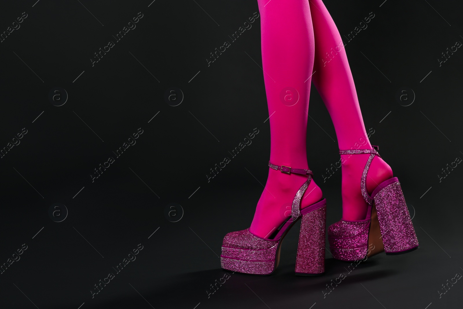 Photo of Woman wearing pink tights and high heeled shoes with platform and square toes on black background, closeup. Space for text