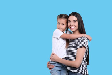Photo of Happy woman with her cute daughter on light blue background, space for text. Mother's day celebration