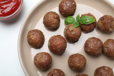 Photo of Tasty cooked meatballs with basil on white table, flat lay
