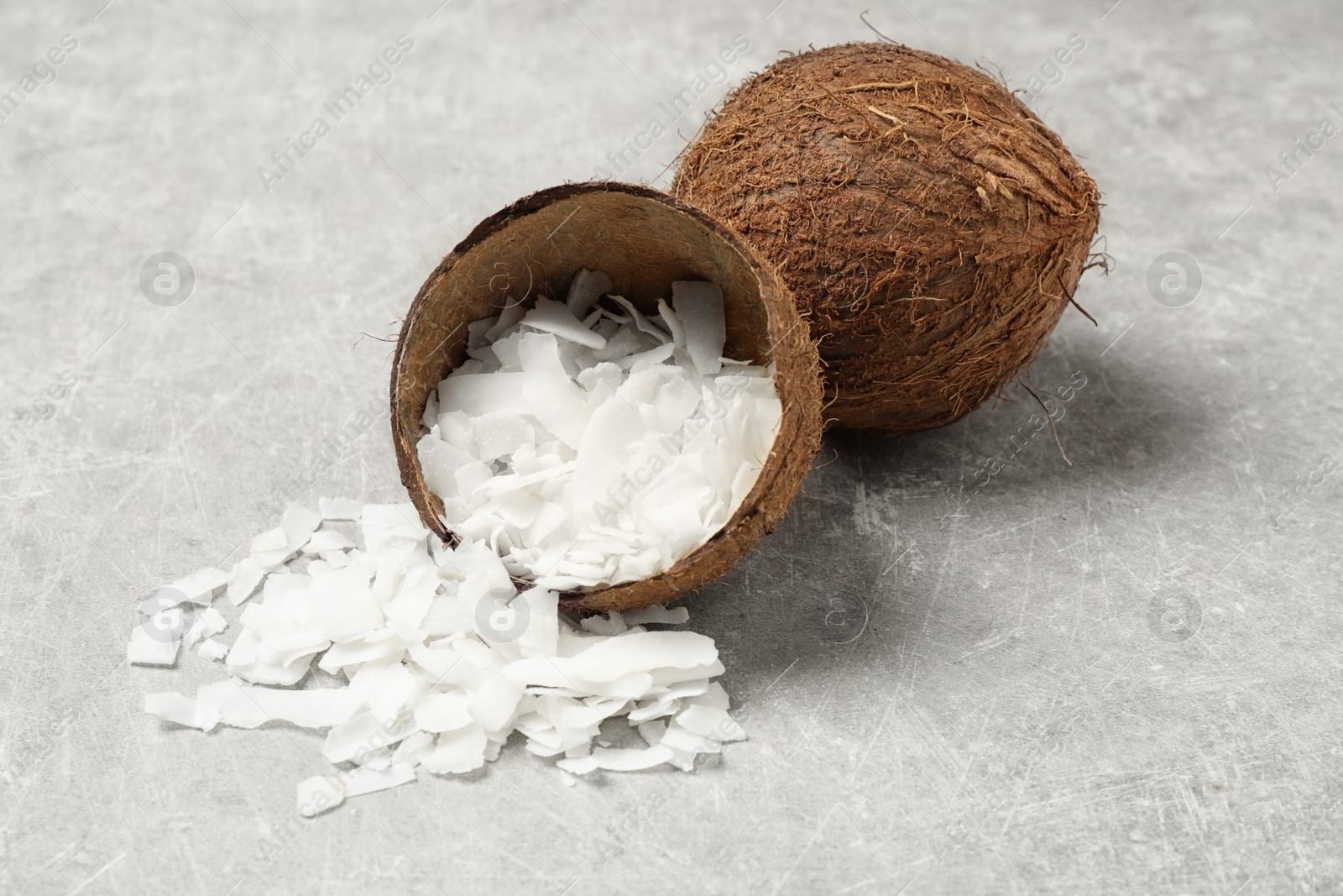 Photo of Tasty coconut chips and shell on grey table