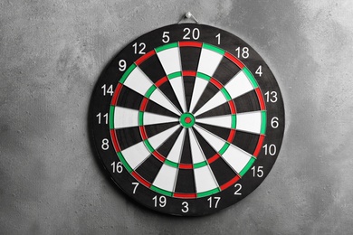 Photo of Dart board hanging on grey textured wall