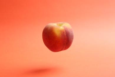 Fresh ripe juicy peach on coral background