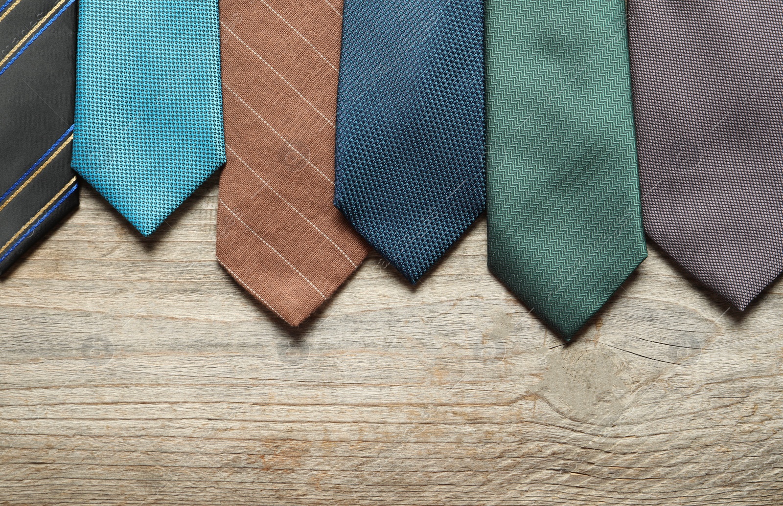 Photo of Different neckties on light wooden table, flat lay