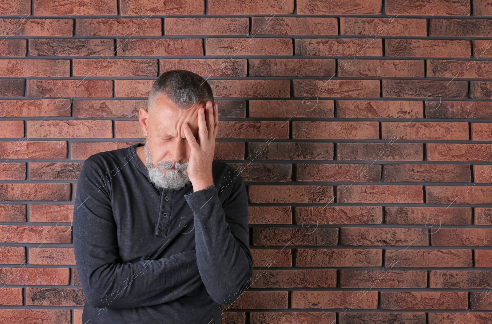 Photo of Senior man in state of depression near brick wall