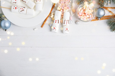 Image of Flat lay composition with funny snowmen made of marshmallows on white wooden table, space for text. Bokeh effect 