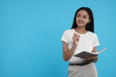 Beautiful secretary with notebook and pen on light blue background, space for text