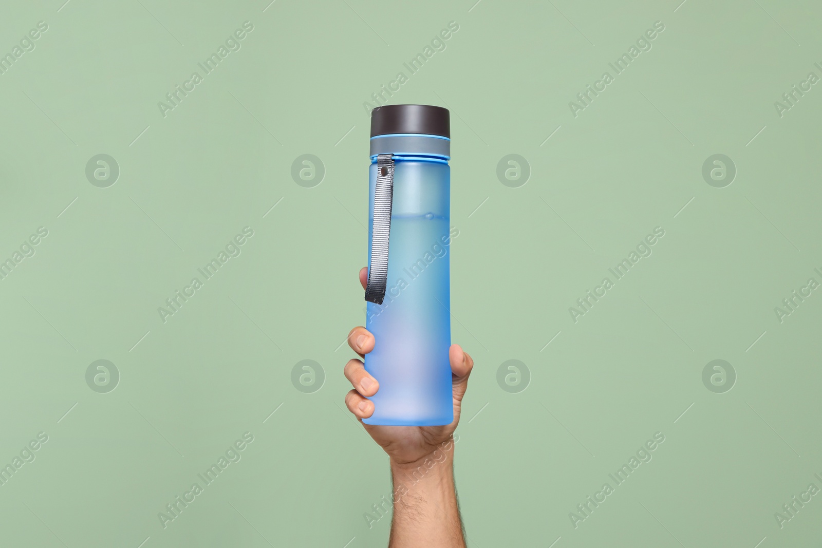 Photo of Man holding transparent plastic bottle of water on light green background, closeup