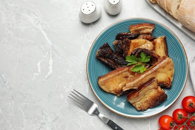 Tasty fried pork lard with parsley on light table, flat lay. Space for text