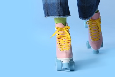 Photo of Woman with vintage roller skates on color background, closeup. Space for text