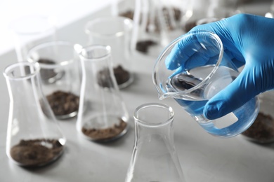 Photo of Scientist preparing soil extract at table, closeup. Laboratory research