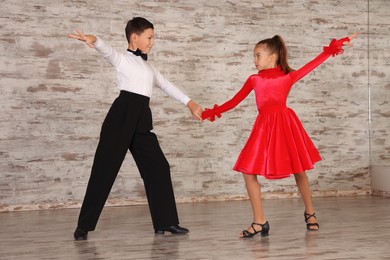 Beautifully dressed couple of kids dancing together in studio