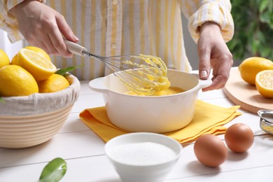 Woman cooking lemon curd at white wooden table, closeup