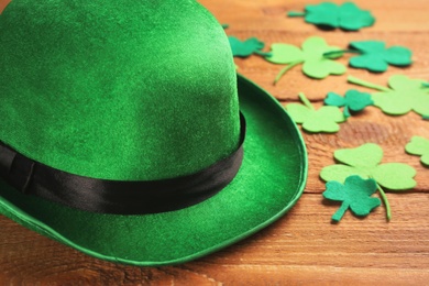 Photo of Leprechaun's hat and decorative clover leaves on wooden background, closeup. St. Patrick's day celebration