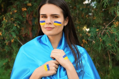 Photo of Young beautiful woman with Ukrainian flag outdoors