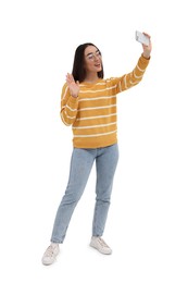 Smiling young woman taking selfie with smartphone on white background