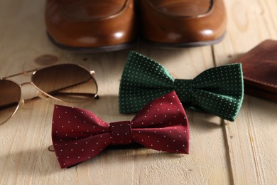 Stylish color bow ties and, sunglasses and shoes on wooden background