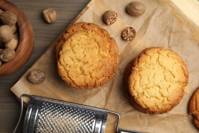 Photo of Tasty cookies, nutmeg seeds and grater on wooden table, flat lay