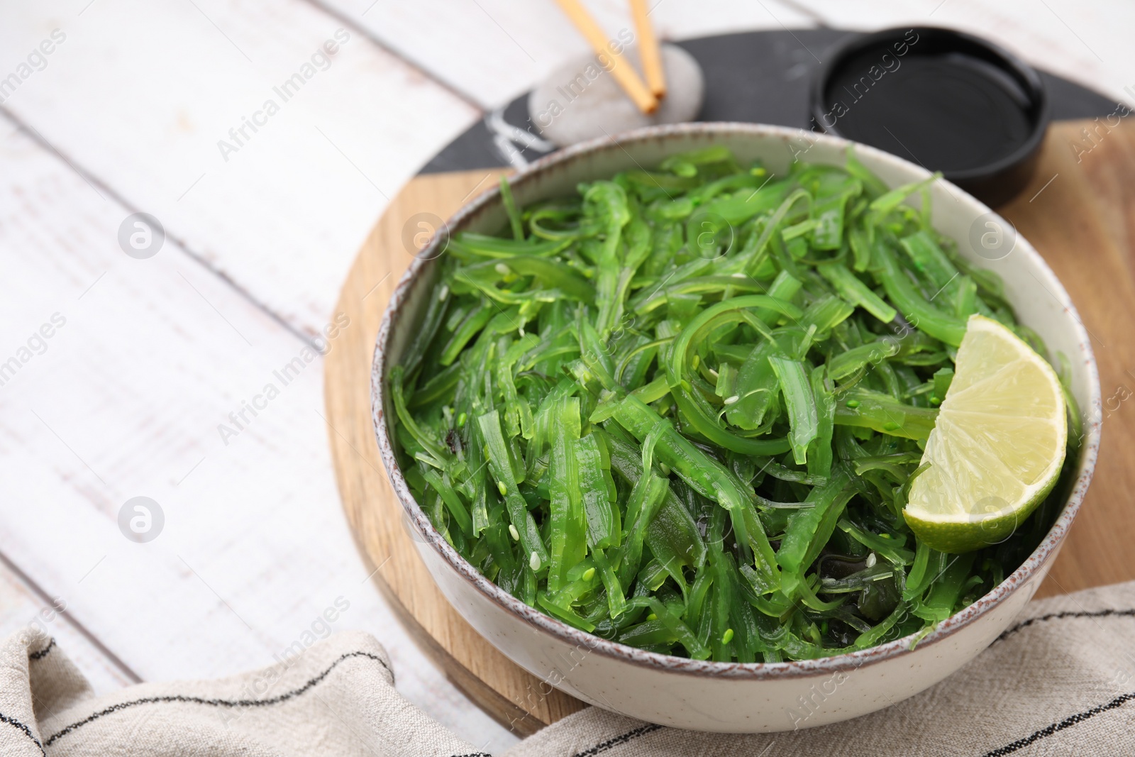 Photo of Tasty seaweed salad in bowl served on wooden table, closeup