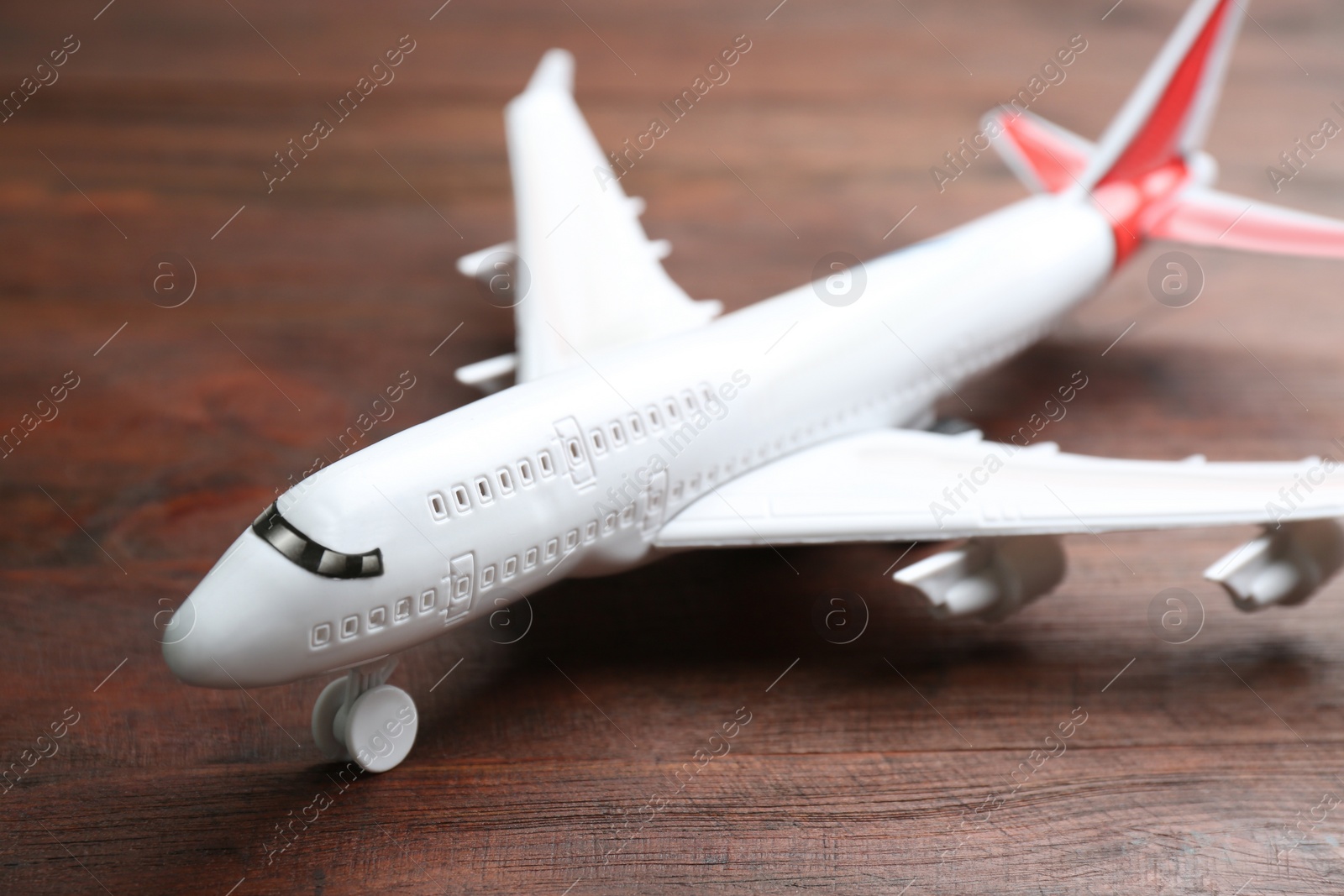Photo of White toy airplane on wooden background, closeup