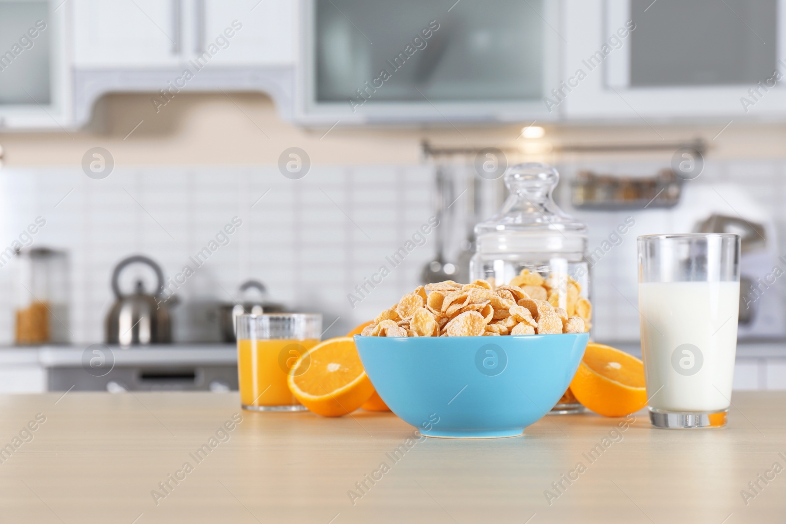 Photo of Cornflakes with glasses of juice and milk on kitchen table