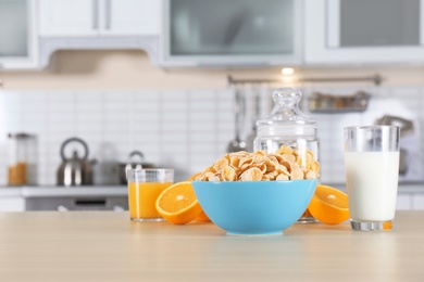 Photo of Cornflakes with glasses of juice and milk on kitchen table