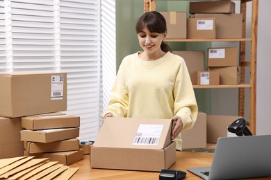 Photo of Post office worker packing parcel at wooden table indoors