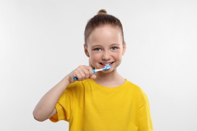 Happy girl brushing her teeth with toothbrush on white background