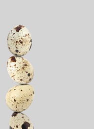 Image of Stacked speckled quail eggs on light grey background. Space for text