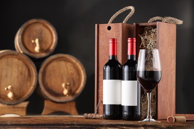 Photo of Wooden boxes, corkscrew and wine bottles on table against dark background. Space for text