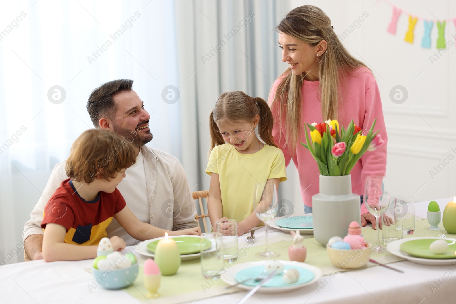 Photo of Happy family celebrating Easter at served table in room