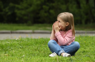 Photo of Little girl suffering from seasonal spring allergy on green grass in park. Space for text