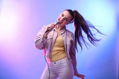 Emotional woman with microphone singing in color lights