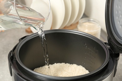 Photo of Water pouring into modern rice cooker in kitchen