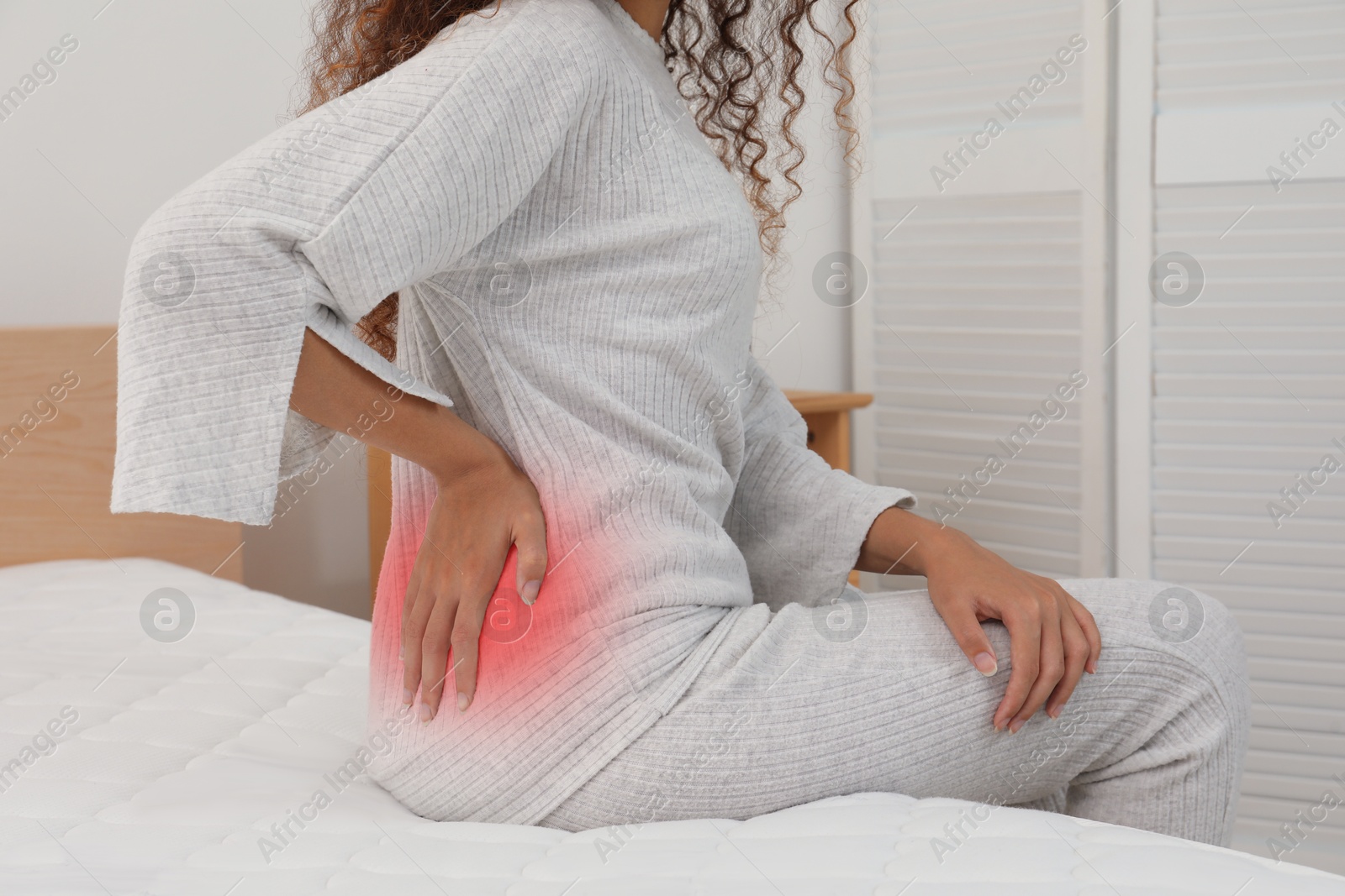 Image of Woman suffering from back pain on bed at home, closeup