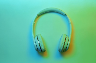 Stylish modern headphones with earmuffs on color background, top view