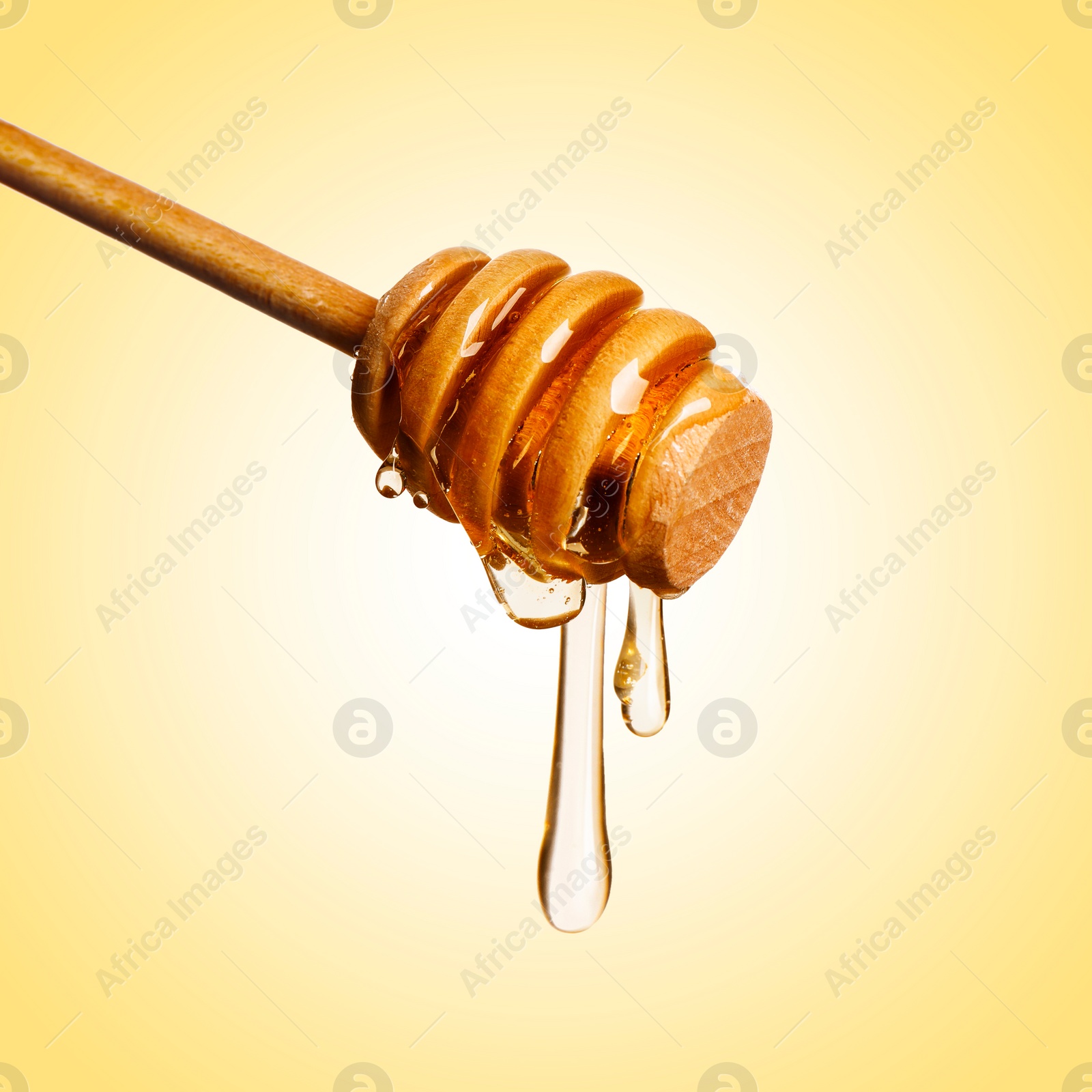 Image of Natural honey dripping from dipper on pale yellow background