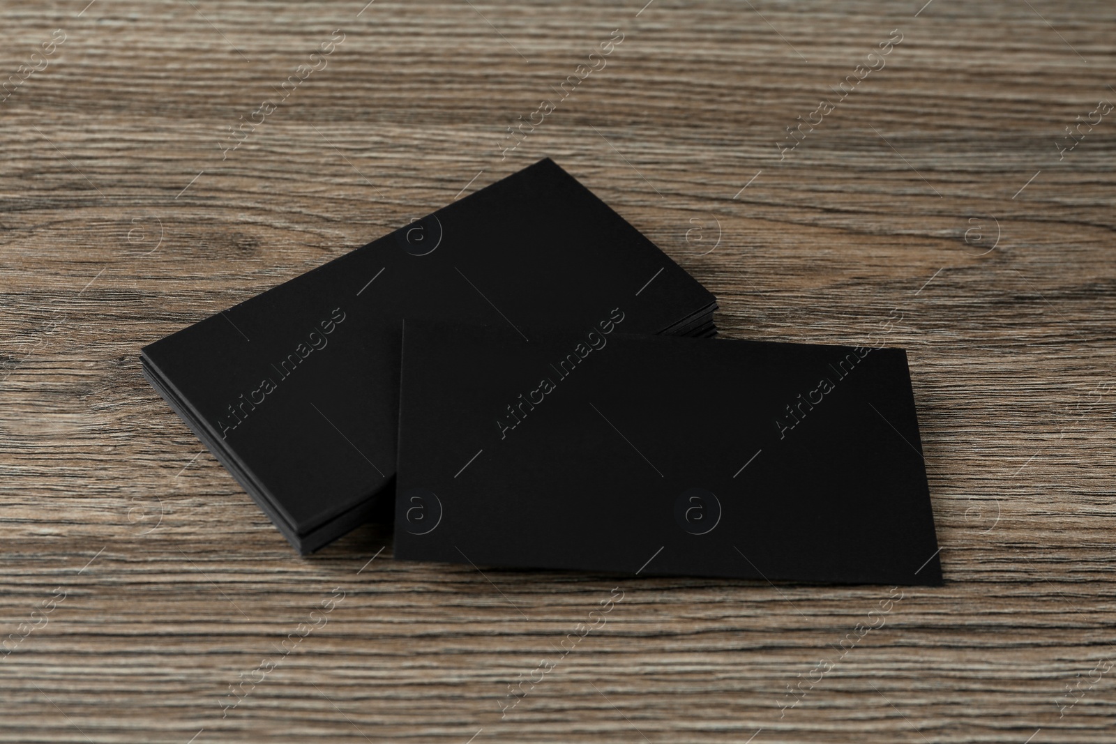 Photo of Blank black business cards on wooden background. Mockup for design