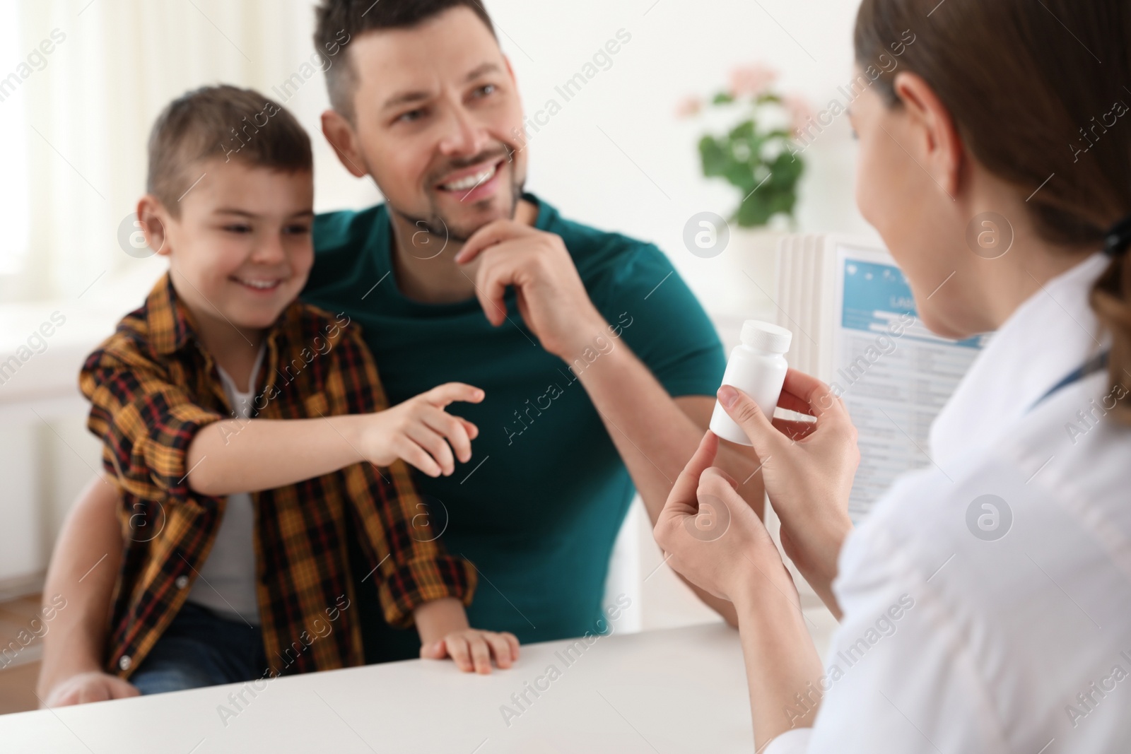 Photo of Father and son visiting pediatrician. Doctor working with little patient in hospital