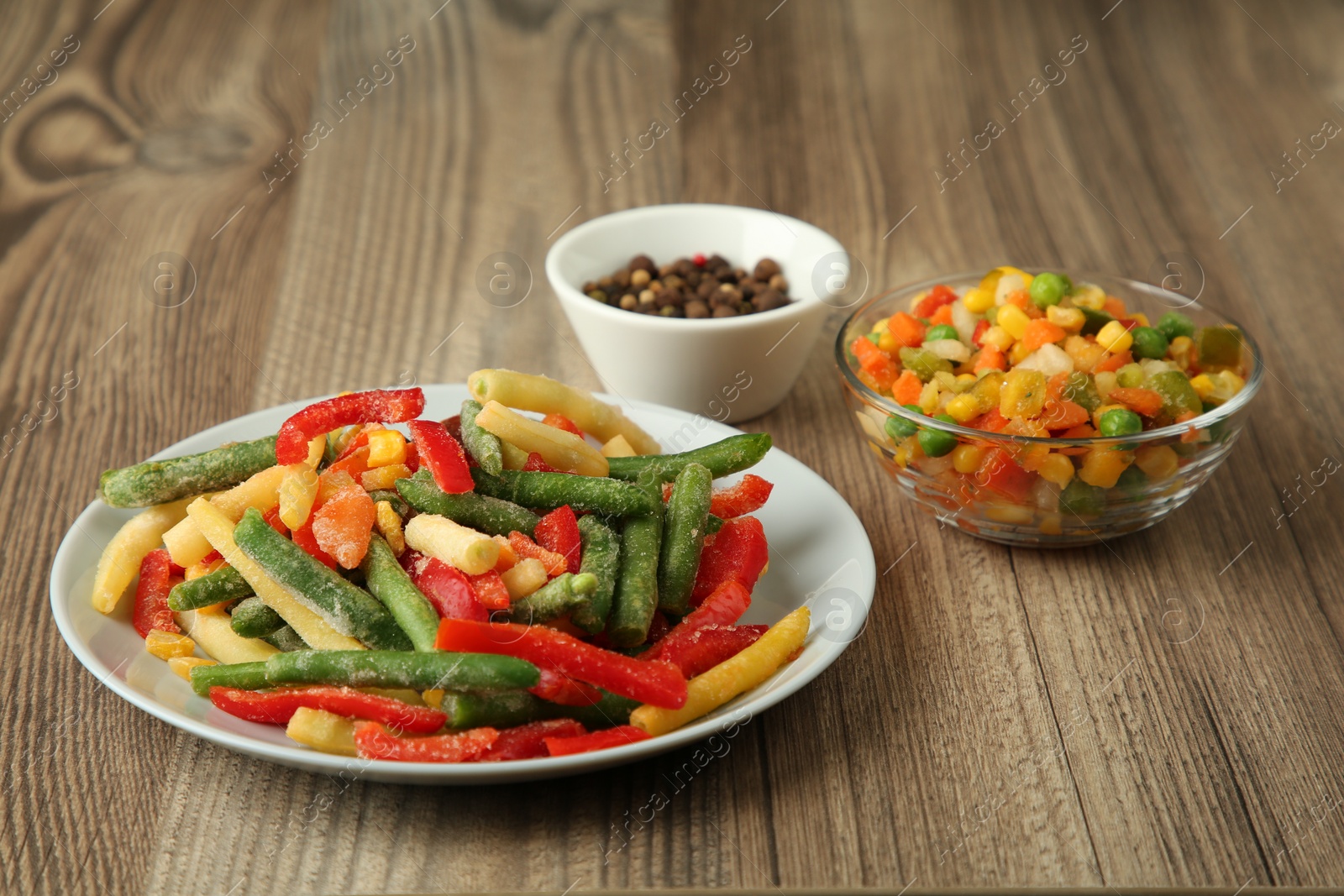Photo of Mix of different frozen vegetables on wooden table, closeup