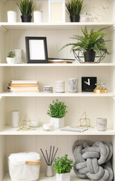 Photo of White shelving unit with plants and different decorative stuff