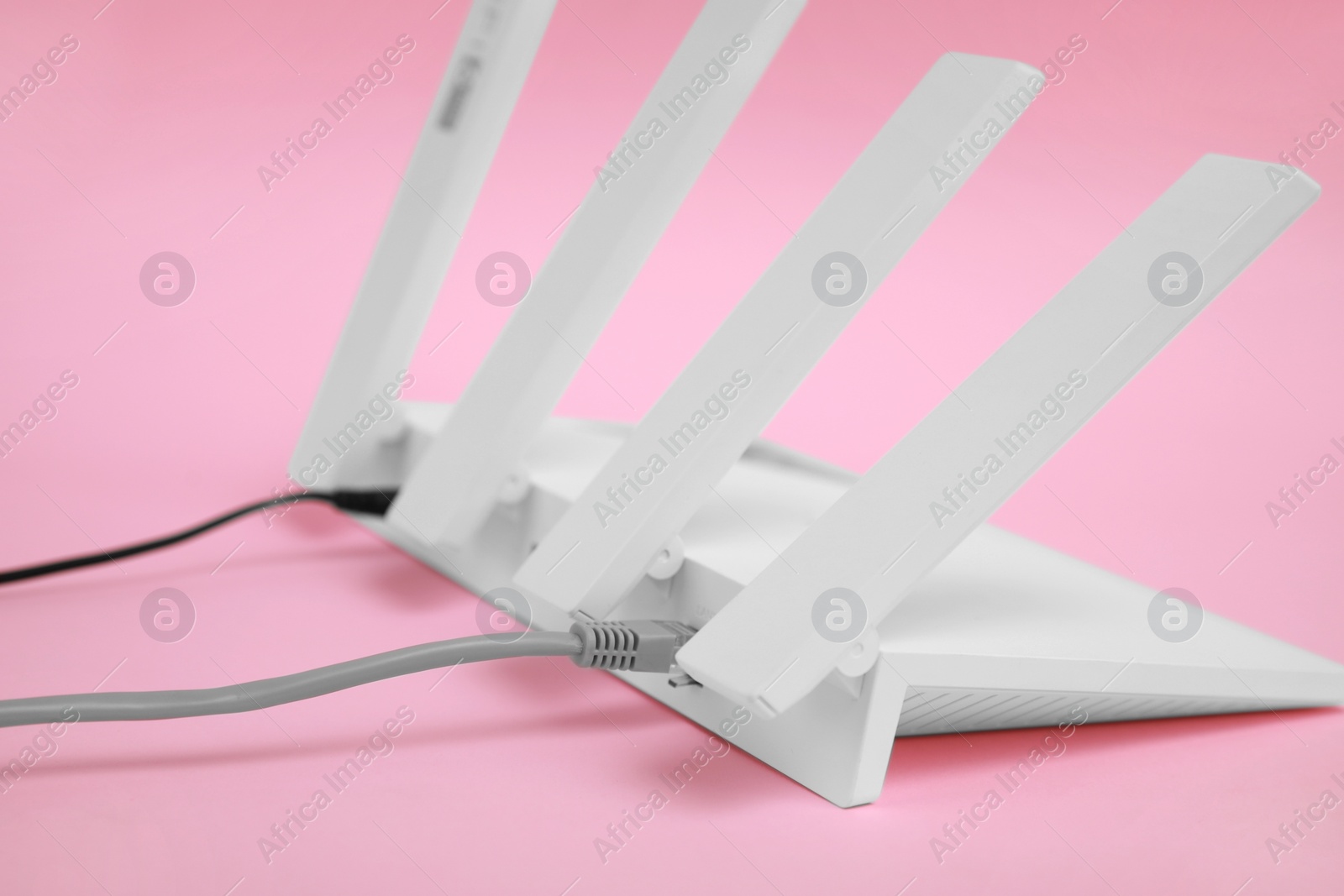 Photo of Modern Wi-Fi router on pink background, closeup