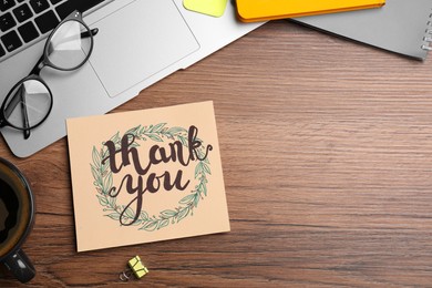Photo of Card with phrase Thank You, laptop, glasses and notebooks on wooden table, flat lay. Space for text