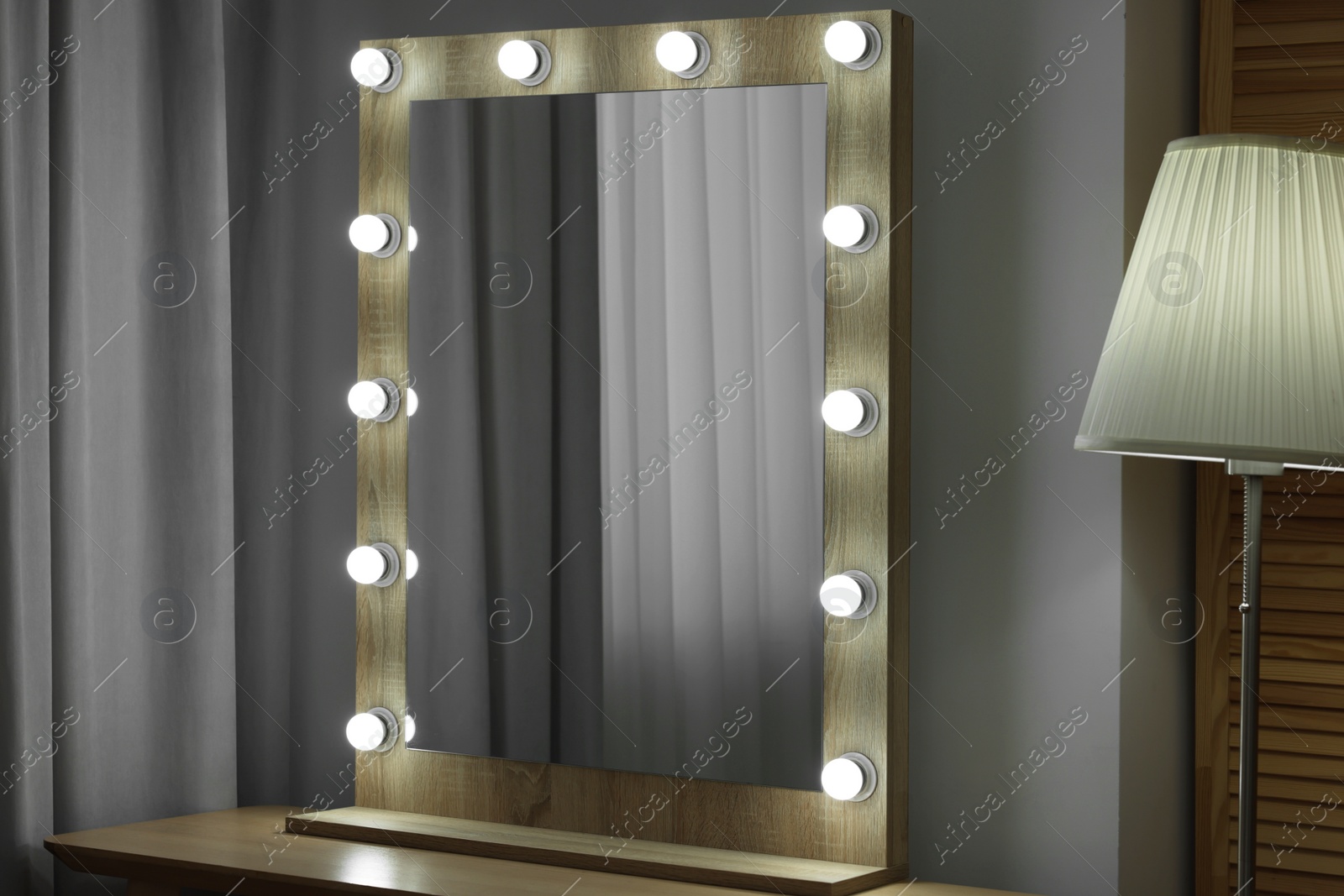 Photo of Beautiful mirror with light bulbs and lamp in makeup room