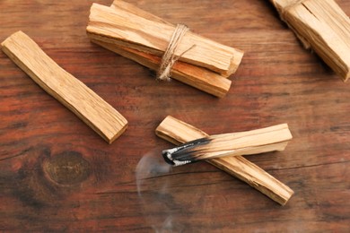 Photo of Palo Santo stick smoldering on wooden table, above view