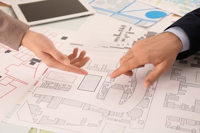 Professional cartographers working with cadastral map at table, closeup