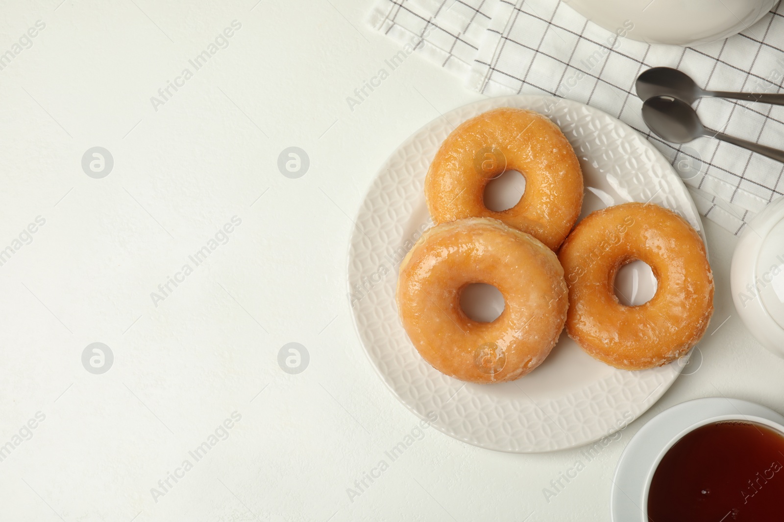 Photo of Delicious donuts on white table, flat lay. Space for text